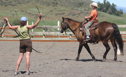 photo of woman directing young person riding a horse