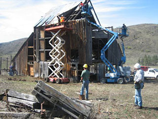 photo of men on lifts dismantling old barn